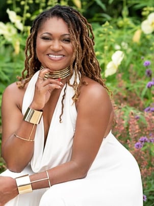 Headshot of Harriet’s Apothecary Coach and Healer Erika Totten, a smiling Black woman with long locs wearing a flowing white dress.