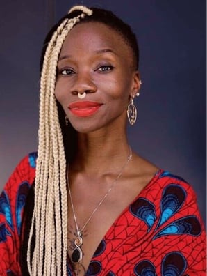 Headshot of Harriet’s Apothecary founder Adaku Utah, a black woman with long blonde braids wearing a colorful printed shirt.