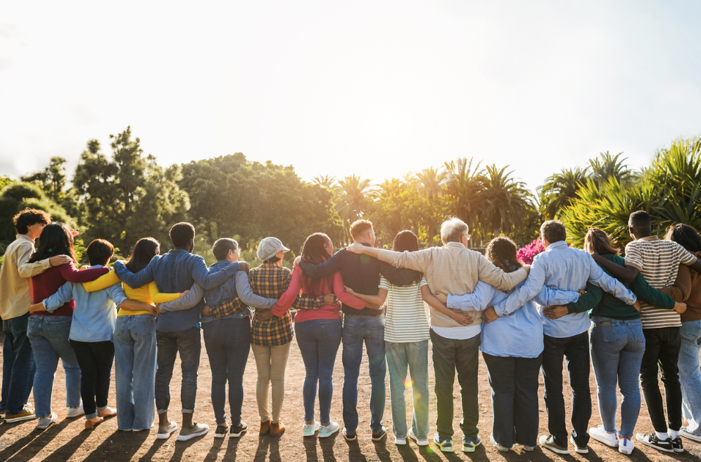 a group of people linking arms in front of a sunset